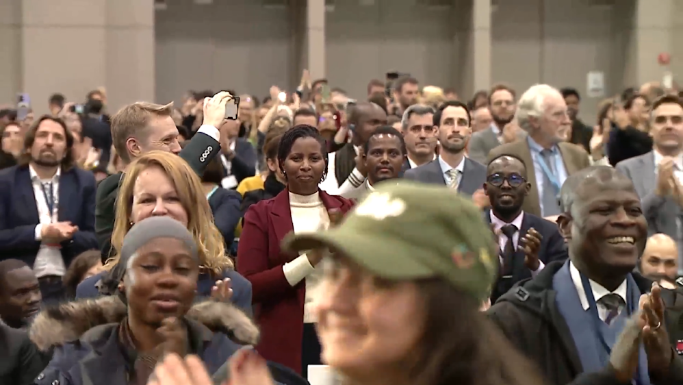 Delegates joining Juliet Kabera (Red jacket, centre) in standing up and applauding for an ambitious treaty (Screenshot: UN Webcast)